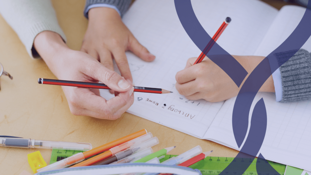 teachers hand holding a pencil and pair of child hands holding a pencil, writing.