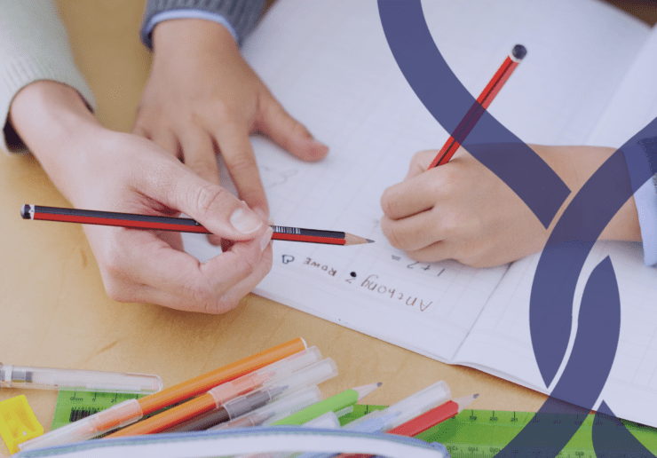 teachers hand holding a pencil and pair of child hands holding a pencil, writing.