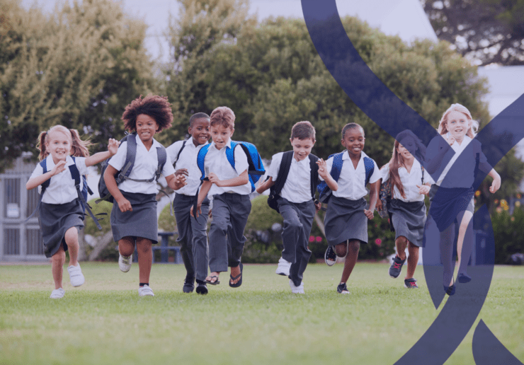 School children in uniform running through a school field outdoors
