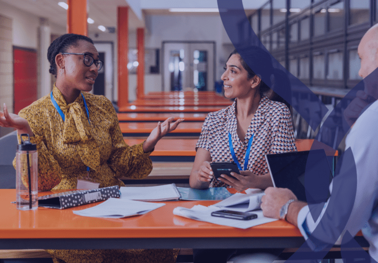 3 Teachers chatting in a room full of empty tables