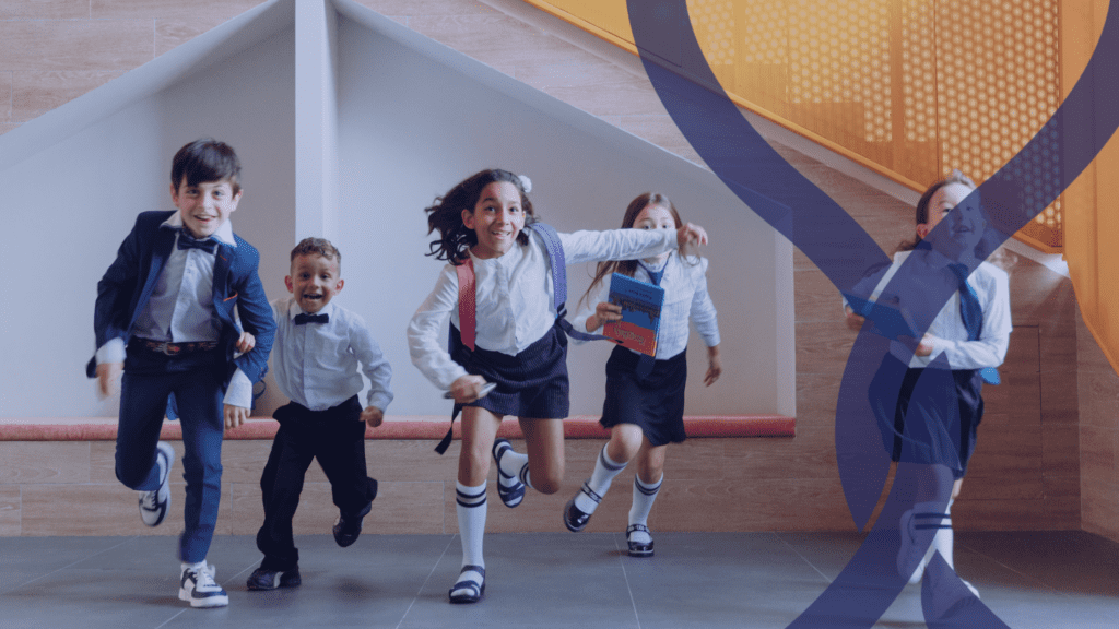 children in uniform running through a school building.