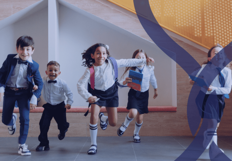children in uniform running through a school building.