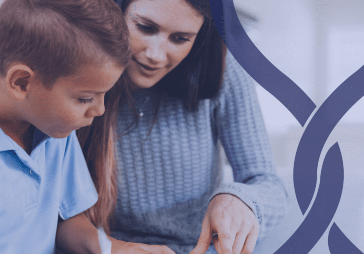 Teacher sat next to a small child listening to them read