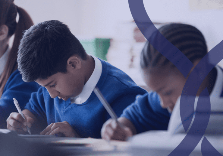 3 children in uniform, writing at desks